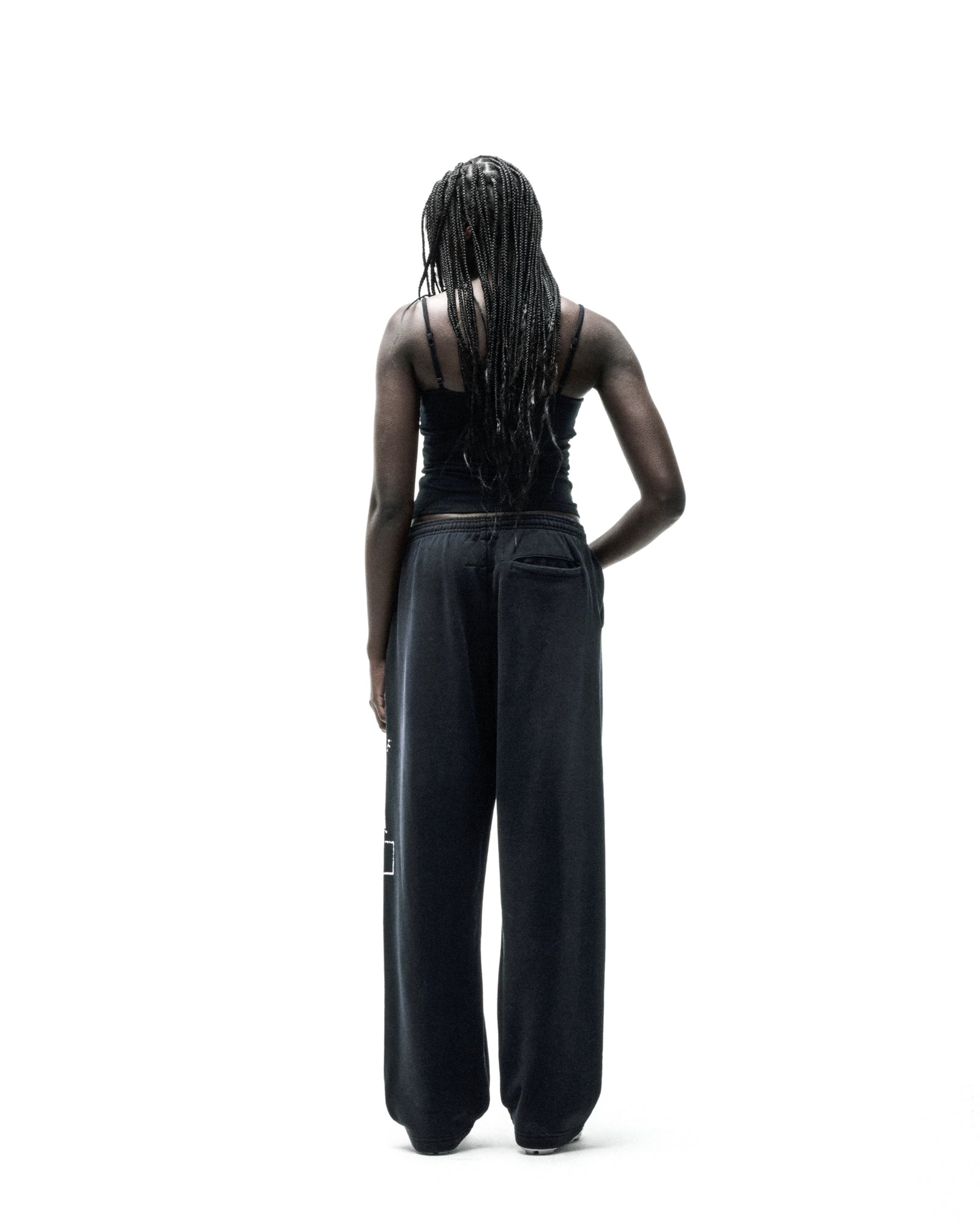 Black ISSUE 404 wide-leg sweatpants with faded graphic print, worn by a person facing away.