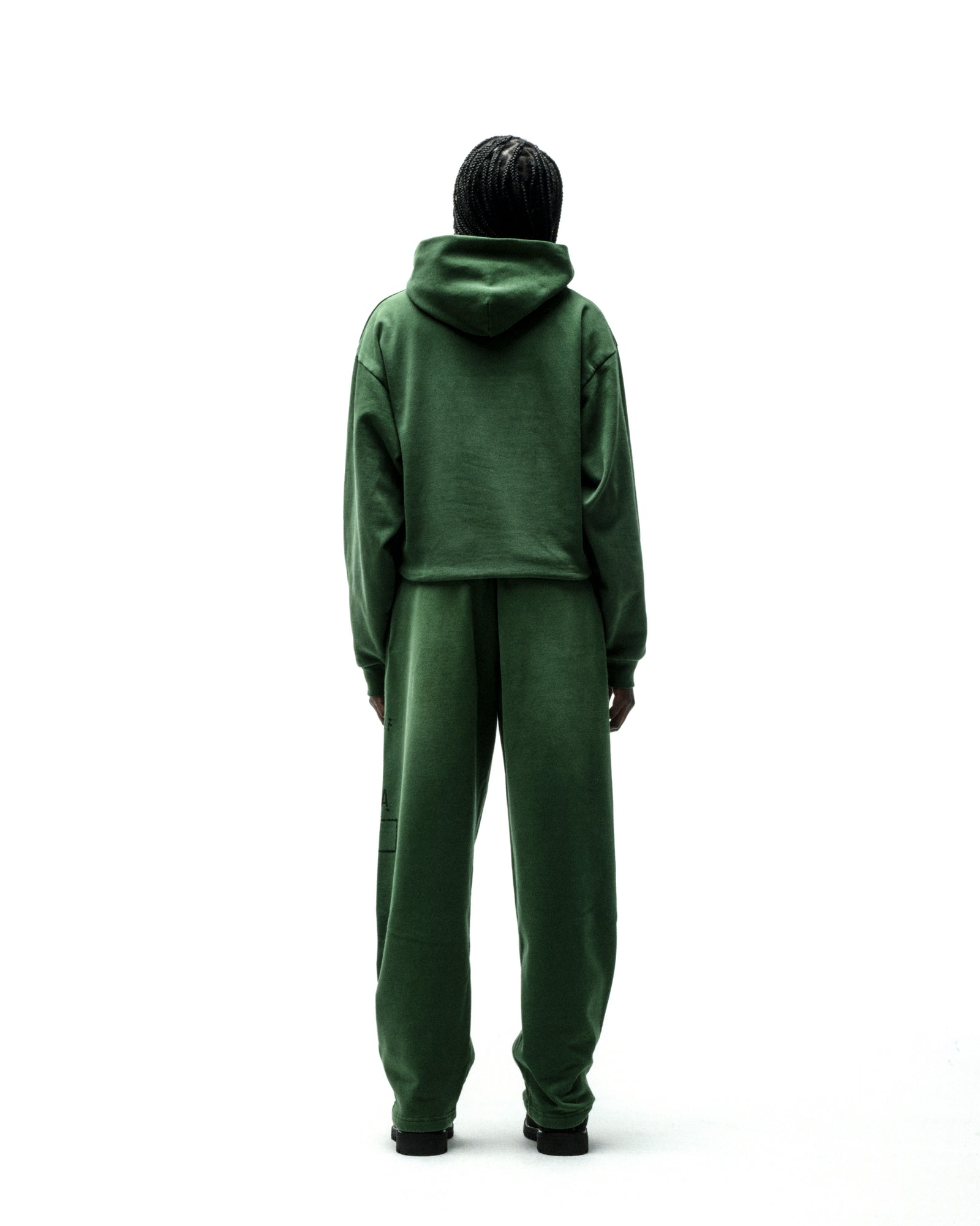 Back view of a person wearing a dark green cotton fleece hoodie and matching sweatpants.