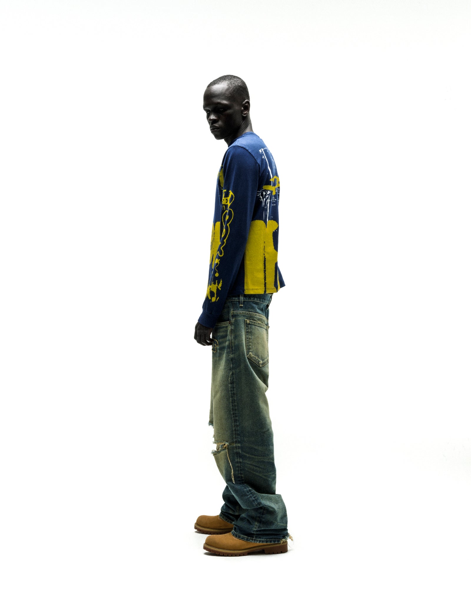 Model wearing a blue 100% cotton X-RAY LONGSLEEVE with yellow graphic print on front, back, and sleeves.