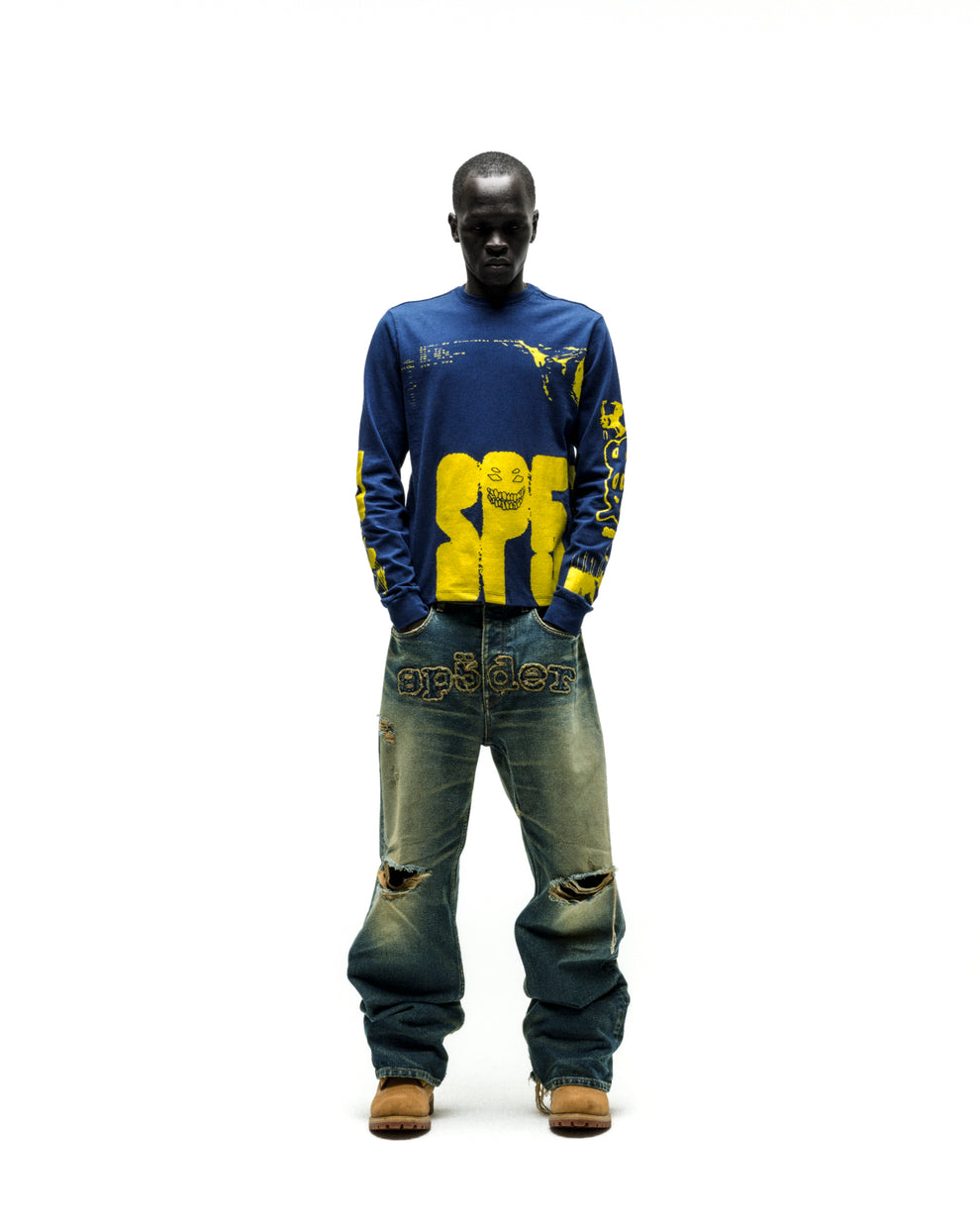 Model in blue X-RAY LONGSLEEVE with yellow graphic print on front, back, and sleeves, paired with distressed jeans.