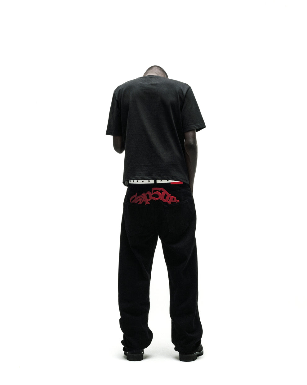 Man in black tee, black corduroy pants with red "Trapstar" embroidery, and a white belt.