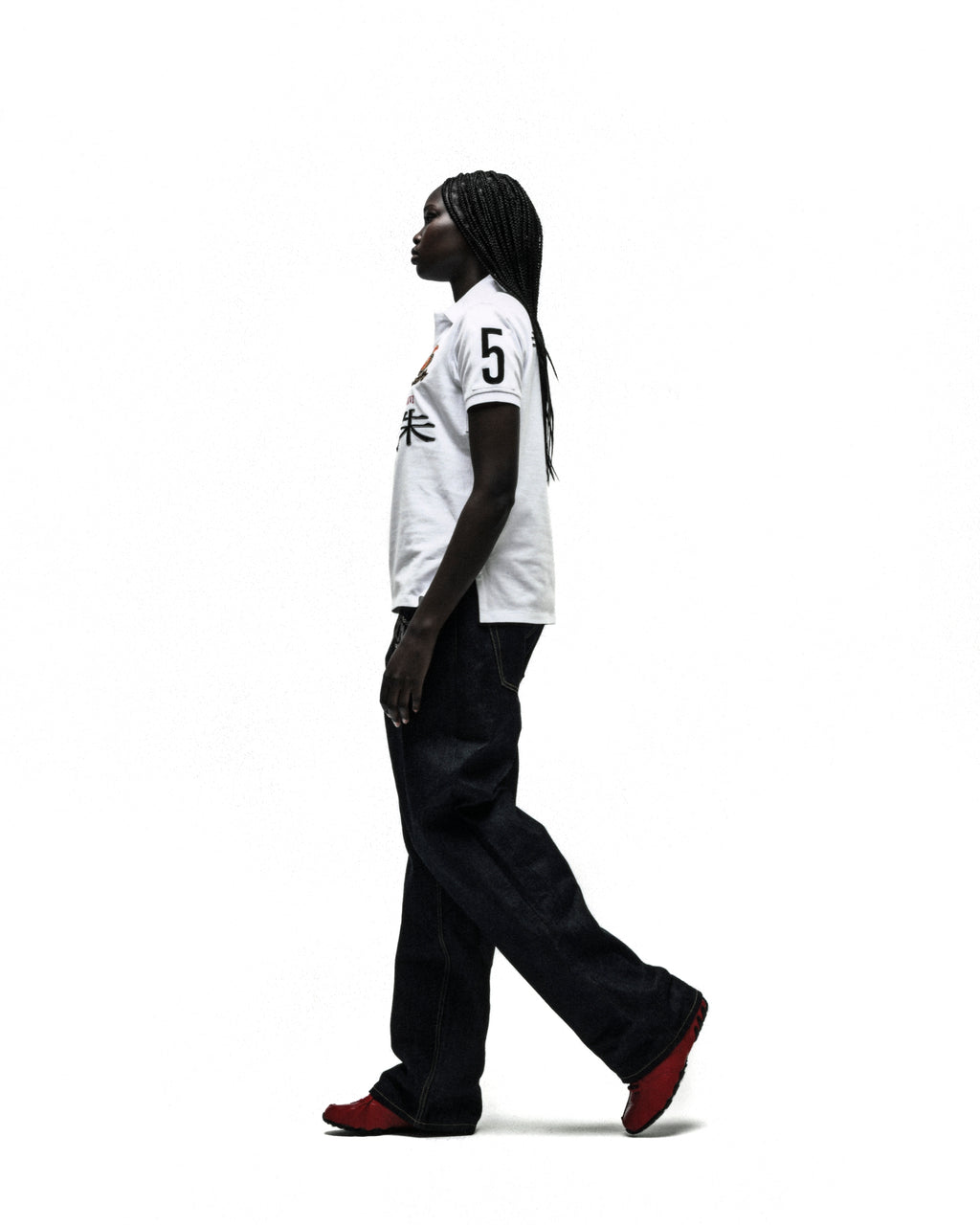 Worldwide Polo white short-sleeve shirt with "5" and red/orange embroidery, paired with dark jeans and red shoes.