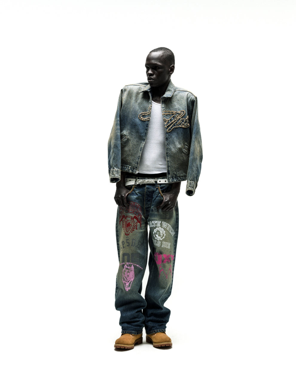 Worn blue denim work jacket with chain embroidery, paired with graphic jeans and a white tee.