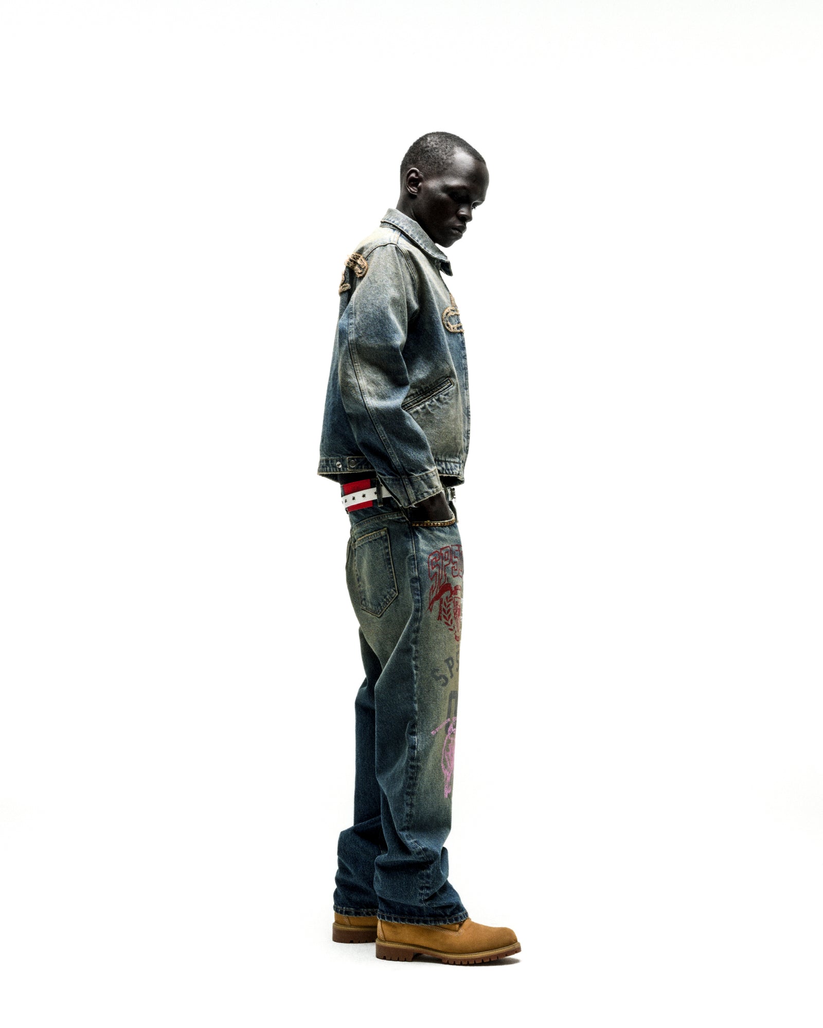 Washed blue denim work jacket with distressed details, worn by a man in matching jeans with red script.