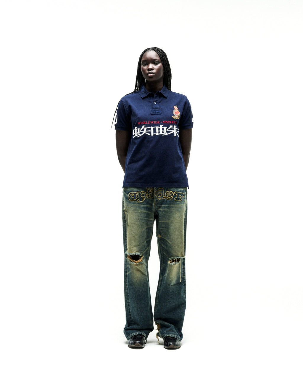 Navy WORLDWIDE POLO with red and white graphic text, worn by a model with distressed denim jeans.