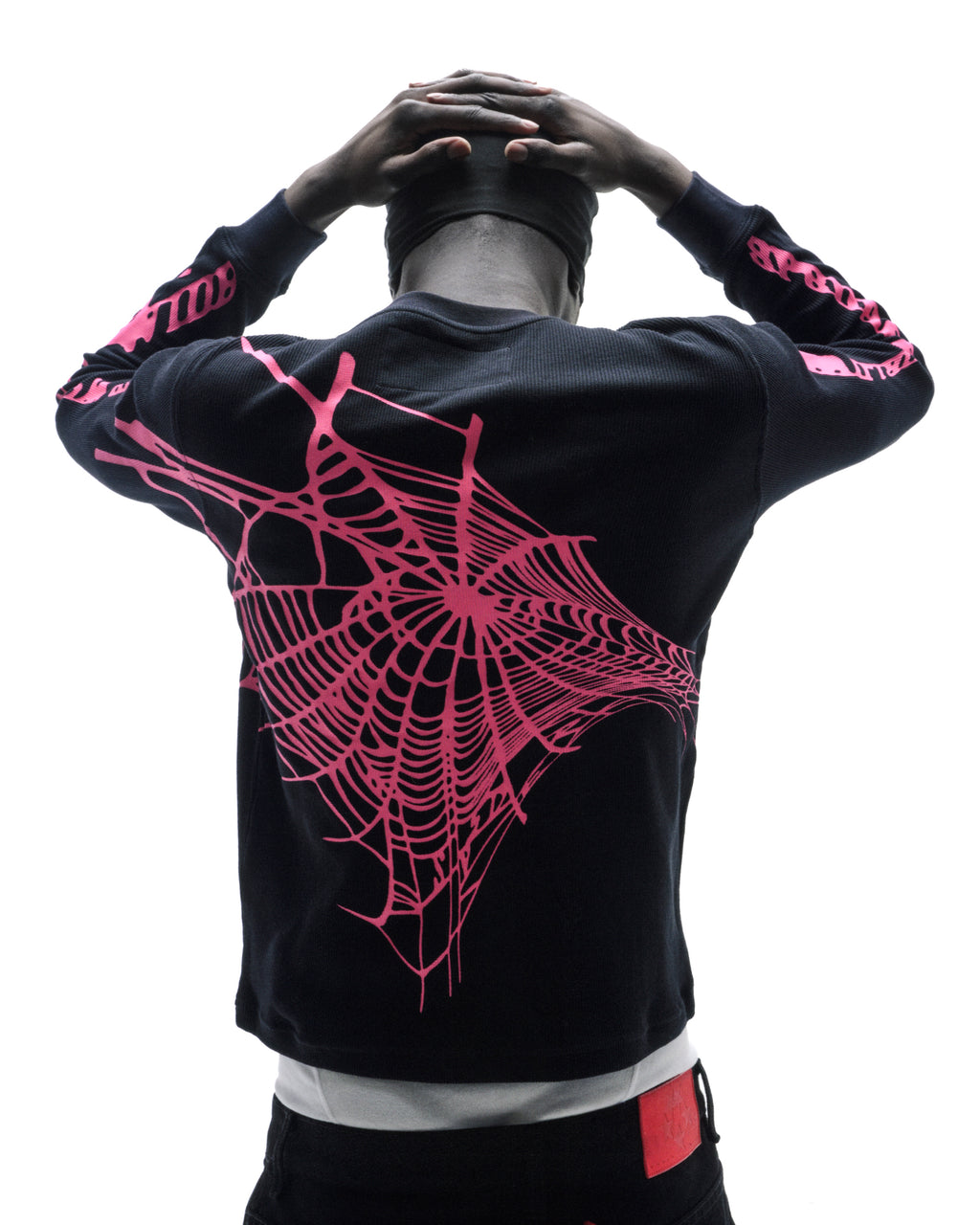 Model wearing a black thermal long-sleeve shirt with a large pink spiderweb graphic on the back and sleeves.