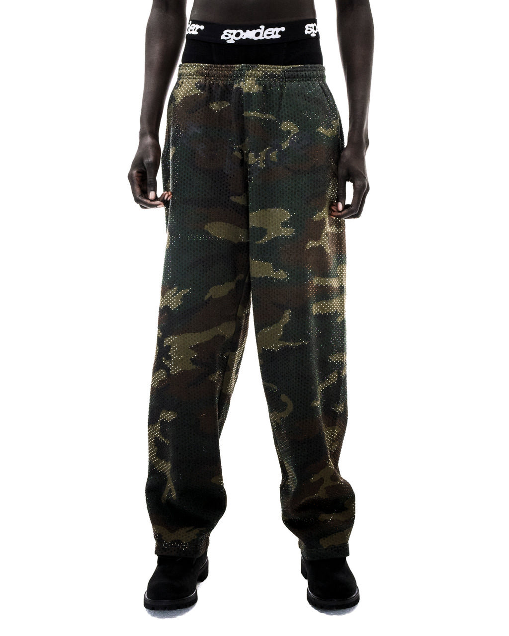 Model wearing camouflage print mesh sweatpants with rhinestone embellishments and a black branded waistband.