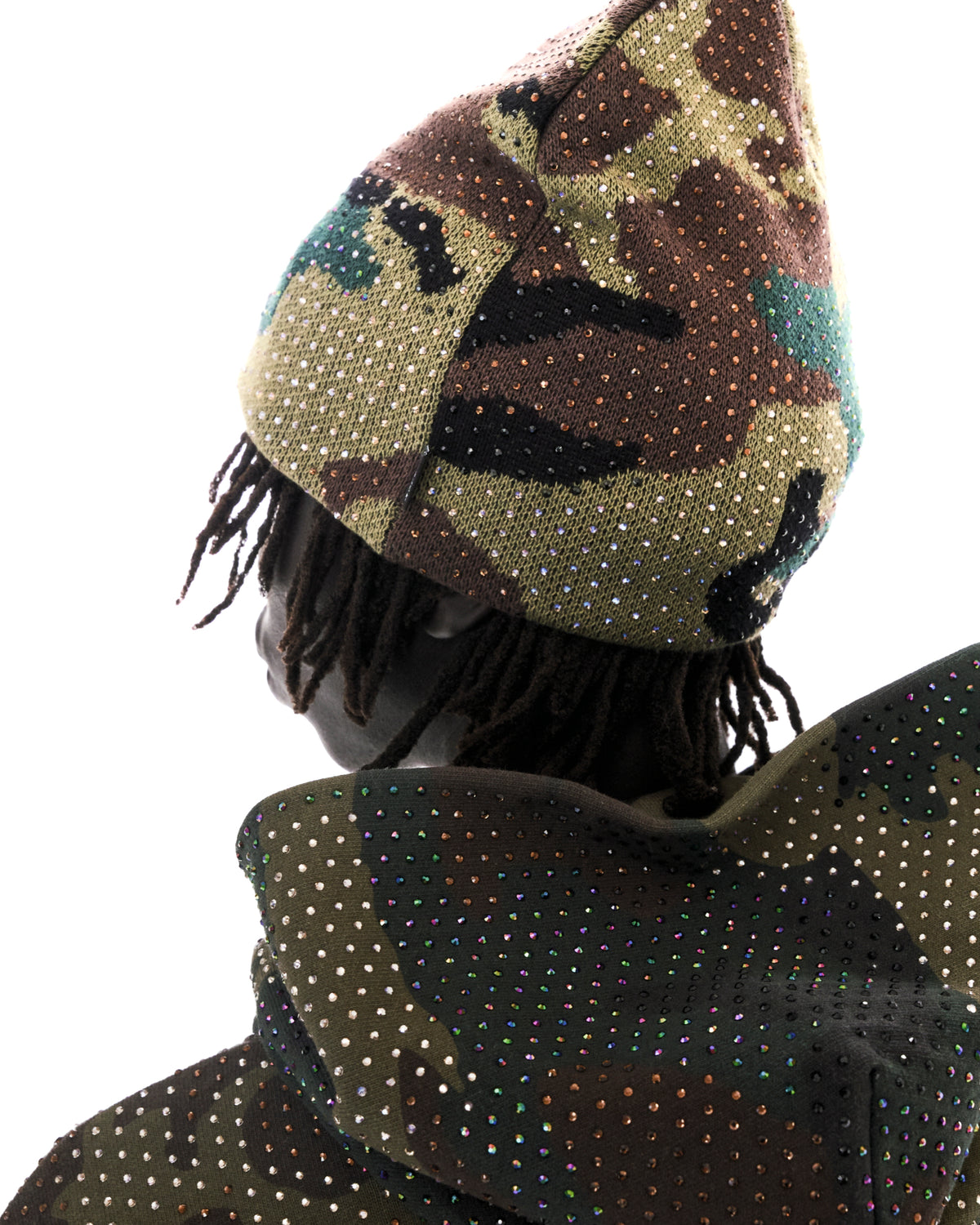 Model wearing a camouflage beanie and matching hoodie embellished with sparkling multicolored rhinestones.