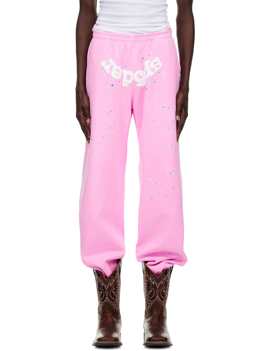 OG WEB PINK SWEATPANT with puff print "Spider" text and scattered star details, worn with cowboy boots.