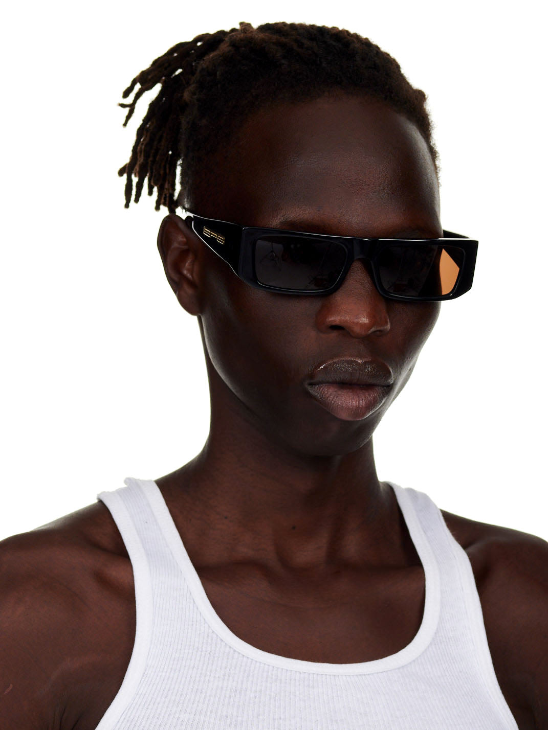 Man wearing black SP5 x FLATLIST 'SLUG' sunglasses with brown lenses and gold temple branding.