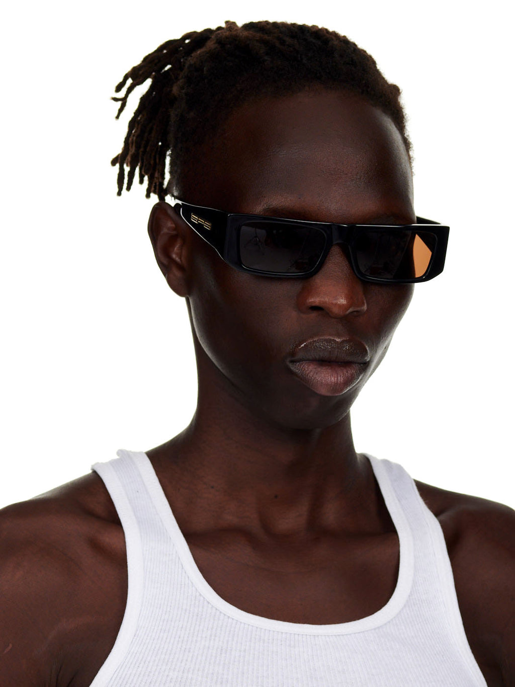 Man wearing black SP5 x FLATLIST 'SLUG' sunglasses with brown lenses and gold temple branding.