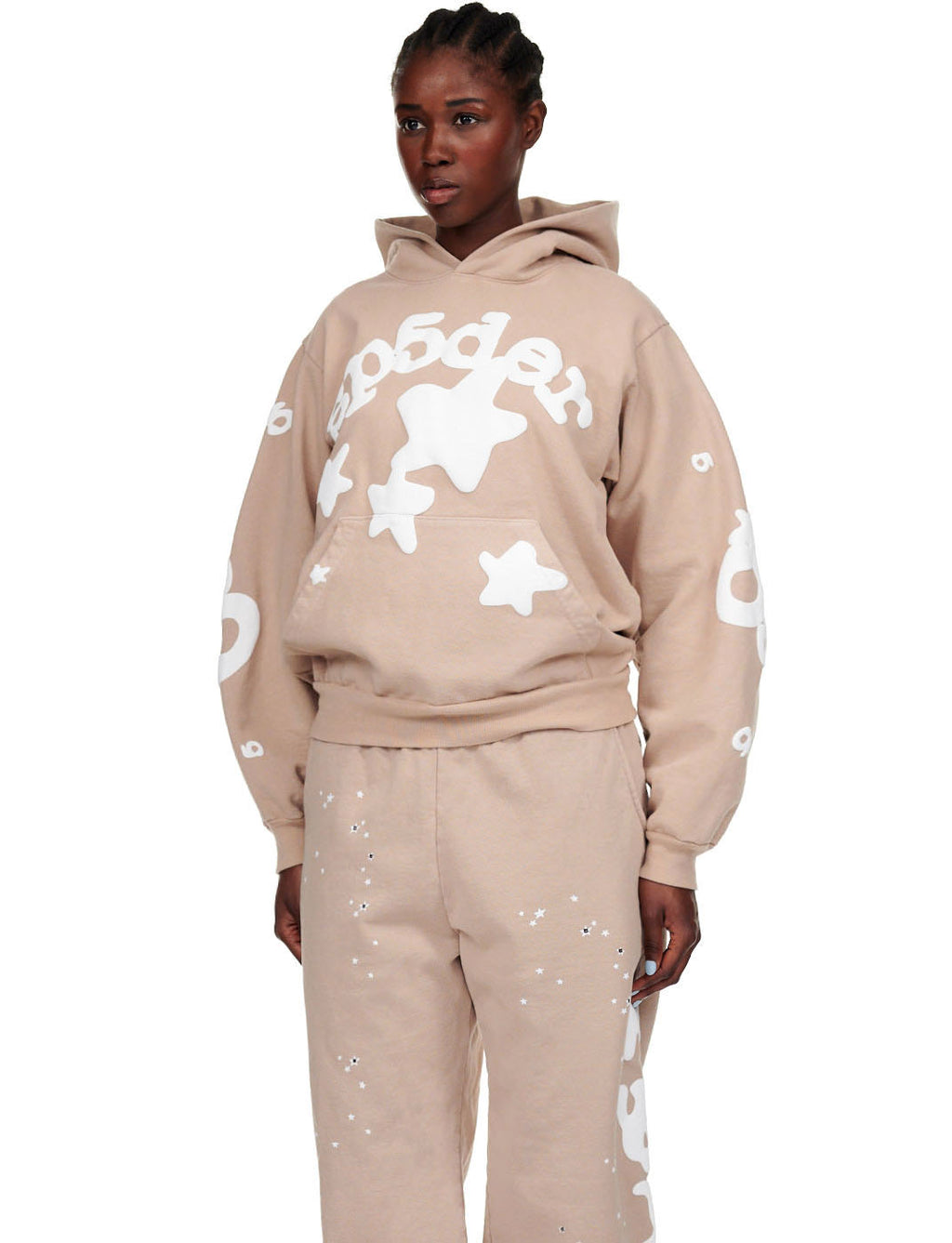 Female model in sand beluga hoodie and sweatpants with white puff print SP5DER text and stars.