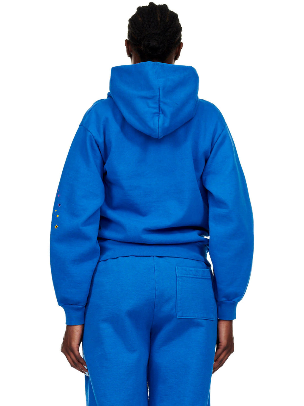 Back view of a person wearing a blue fleece hoodie and sweatpants with colorful stars on the left sleeve.