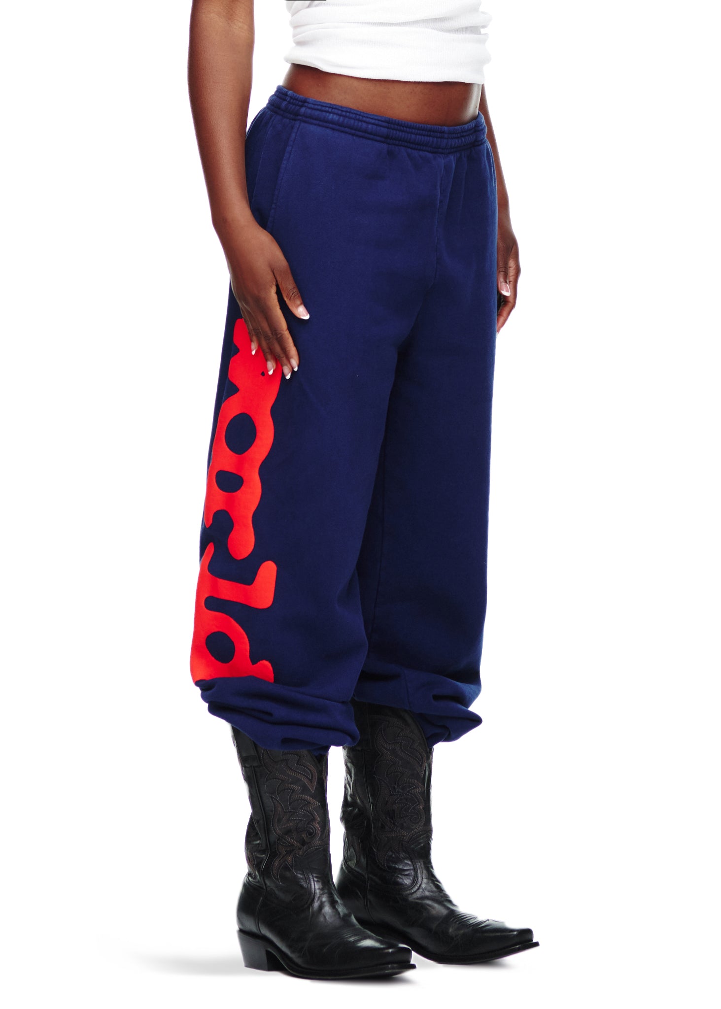 Navy BELUGA SWEATPANT with red "Worldwide" puff/discharge print, worn with black cowboy boots.