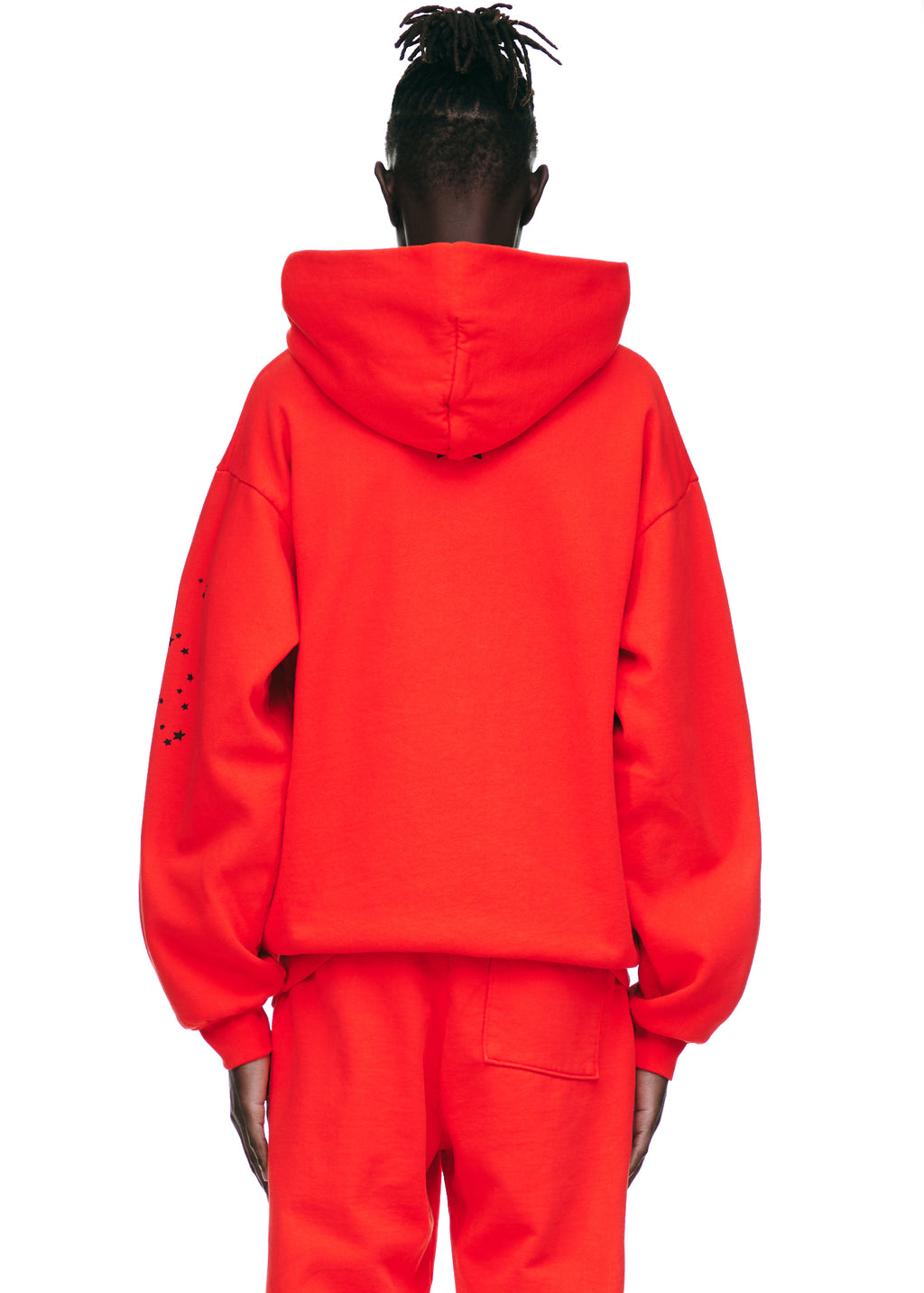 Back view of a red P*NK V2 HOODIE with black star prints on the left sleeve.