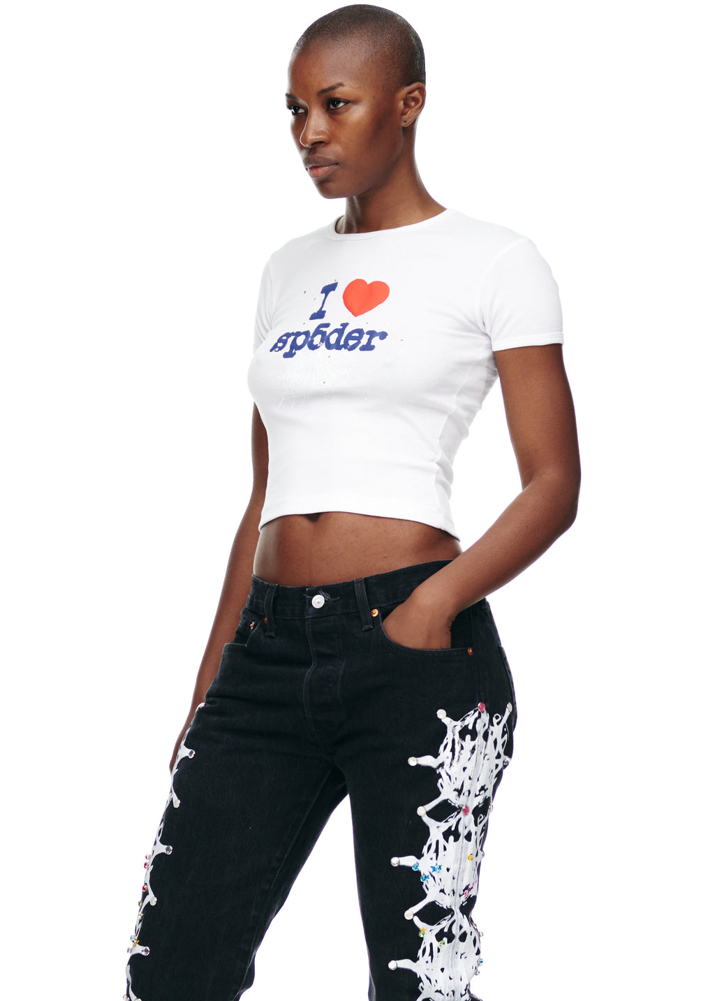 Female model in white cropped cotton "I heart spoder" baby tee and black jeans.