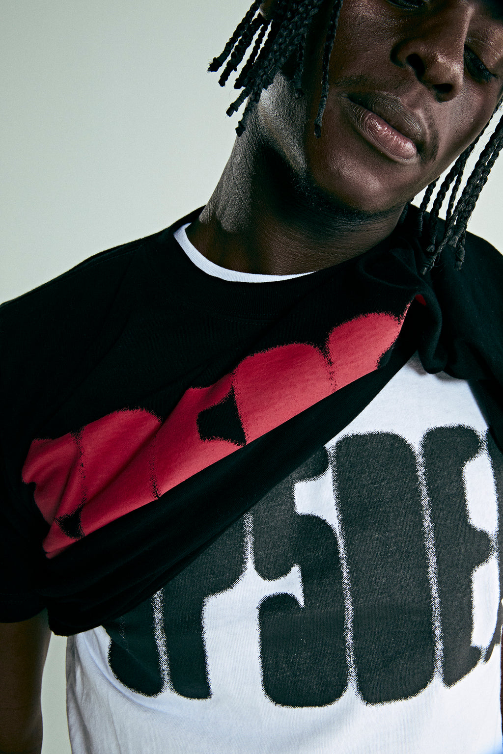 Black male model wearing a white cotton tee with a bold black 'SP5DER' text print.