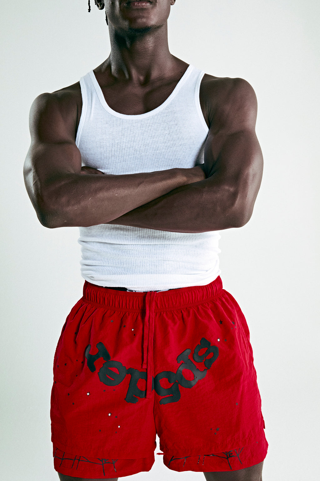 Red OG WEB DOUBLE LAYER SHORT with black "SP5DER" text and star print, worn by a person.