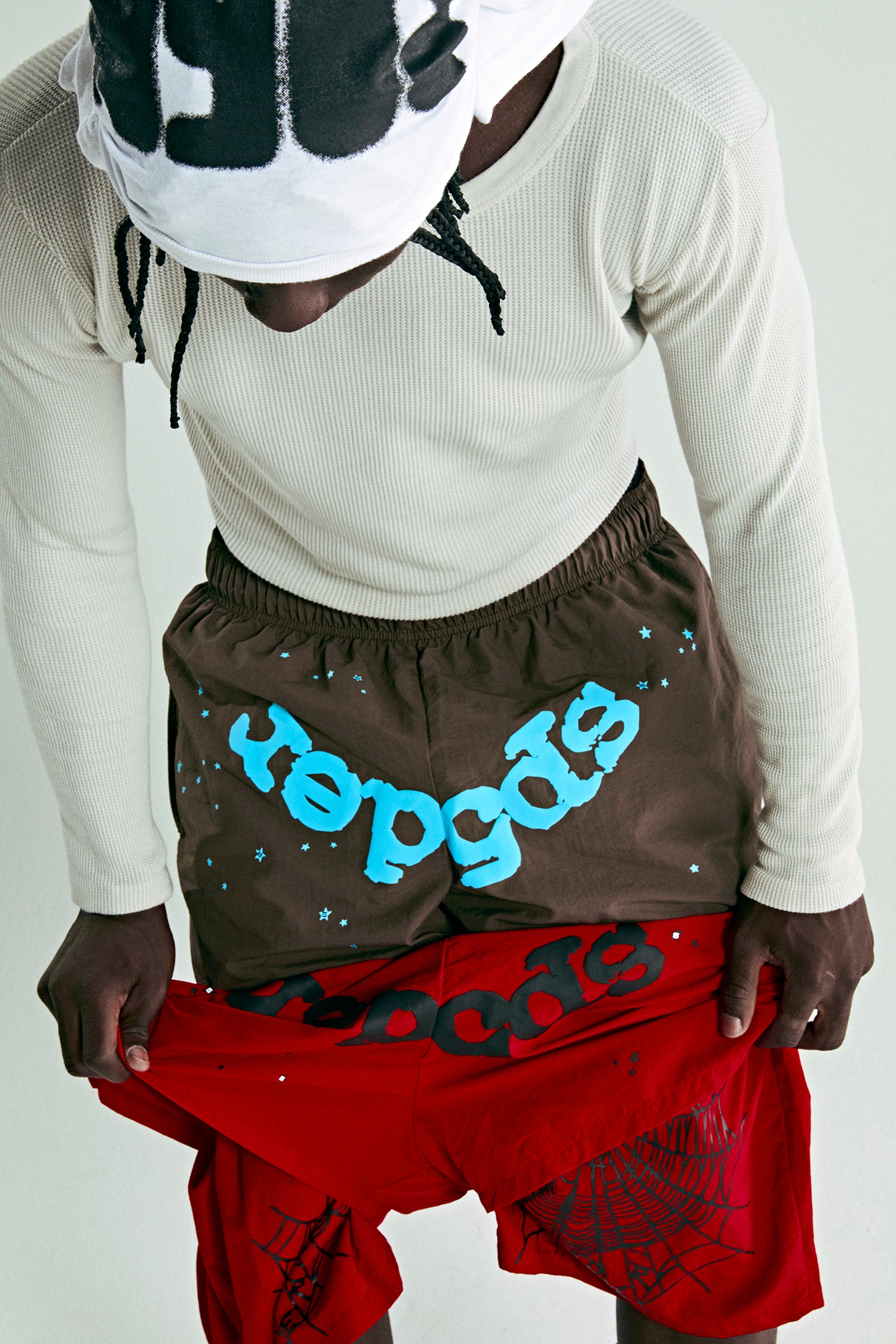 Brown water-repellent nylon shorts with blue "repgods" text and star print, revealing red inner layer.