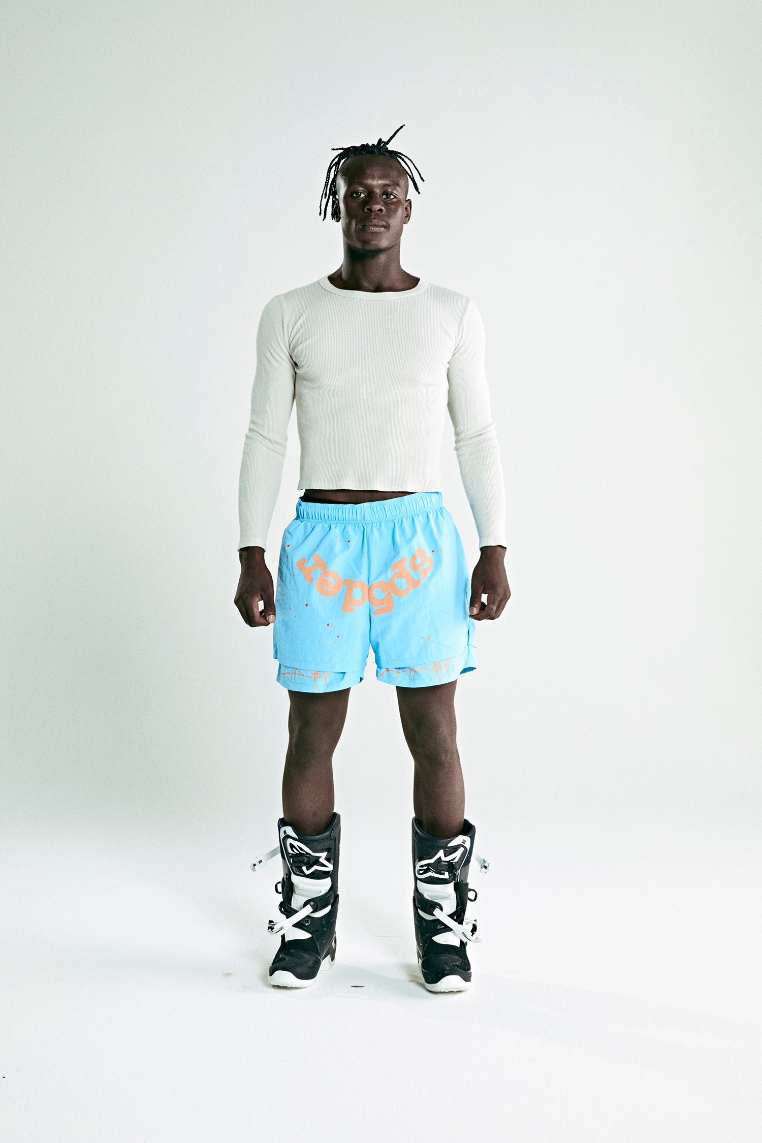 Model wearing OG WEB Double Layer Short in light blue 4oz water repellent nylon with orange SP5DER text and star print.
