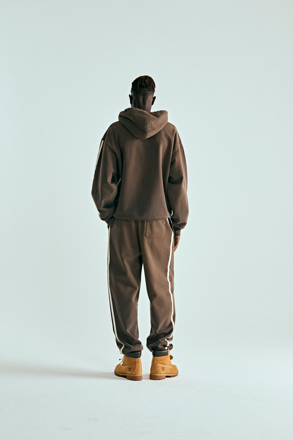 Brown 5STAR Rodeo hoodie and sweatpants set with white side stripes, worn by a person facing away.