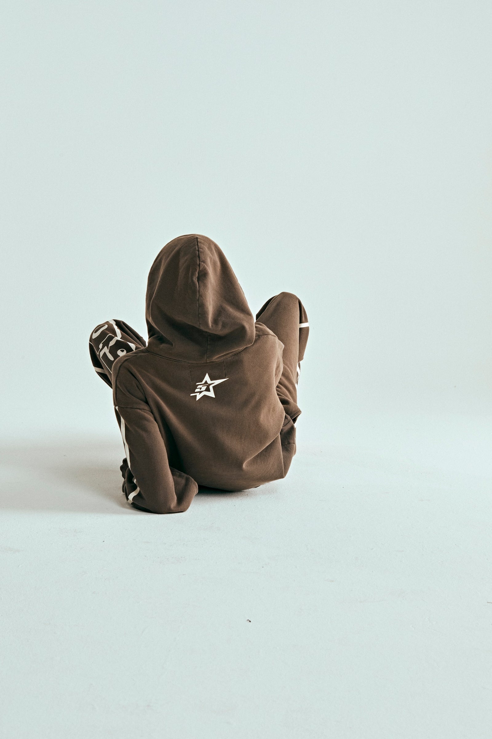 Child in brown 5STAR Rodeo hoodie with white star logo on back, sitting on a light background.