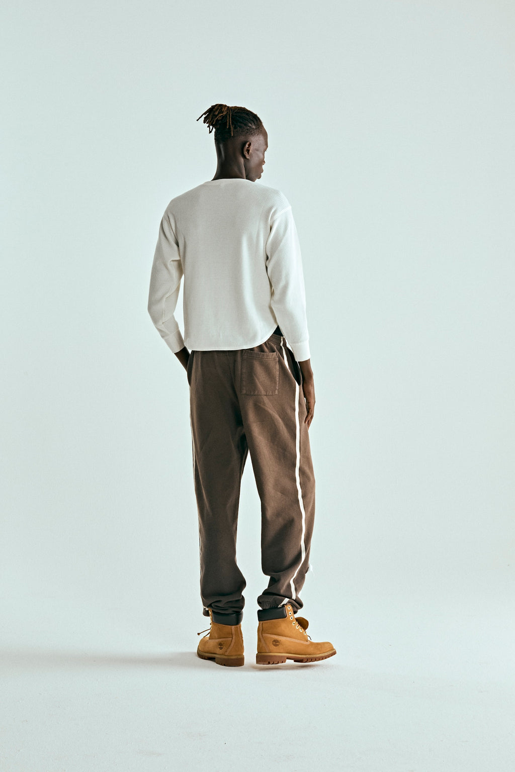 Man in brown 5STAR Rodeo sweatpants with white side stripe, elastic cuffs, and distressed patch.
