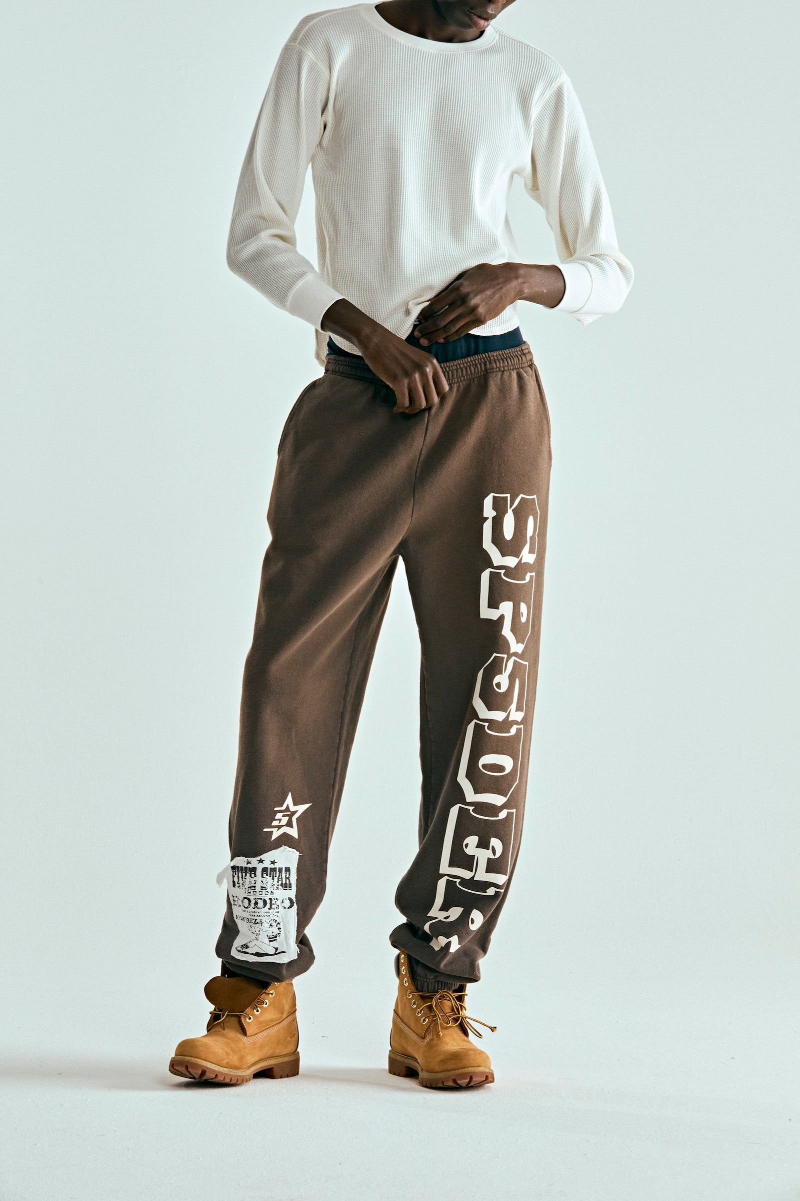 Brown 5STAR RODEO SWEATPANT with white SP5DER text, side stripe, and distressed patch.