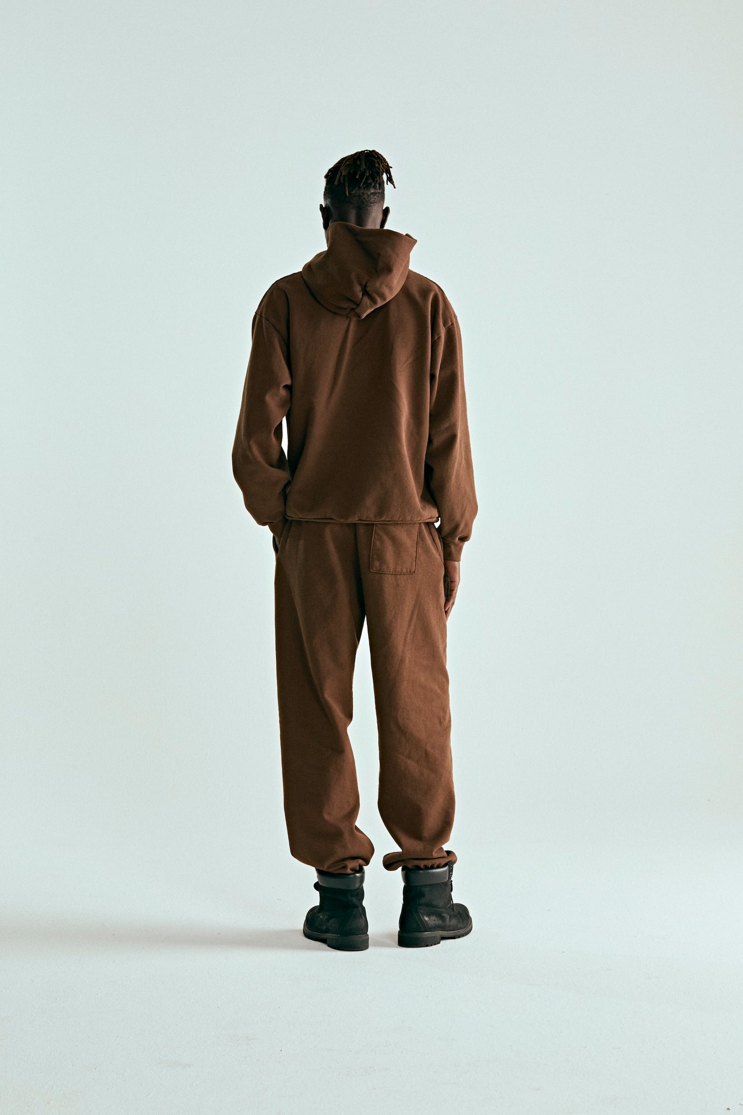 Back view of a person wearing a brown 13oz cotton fleece OG WEB HOODIE and matching sweatpants.