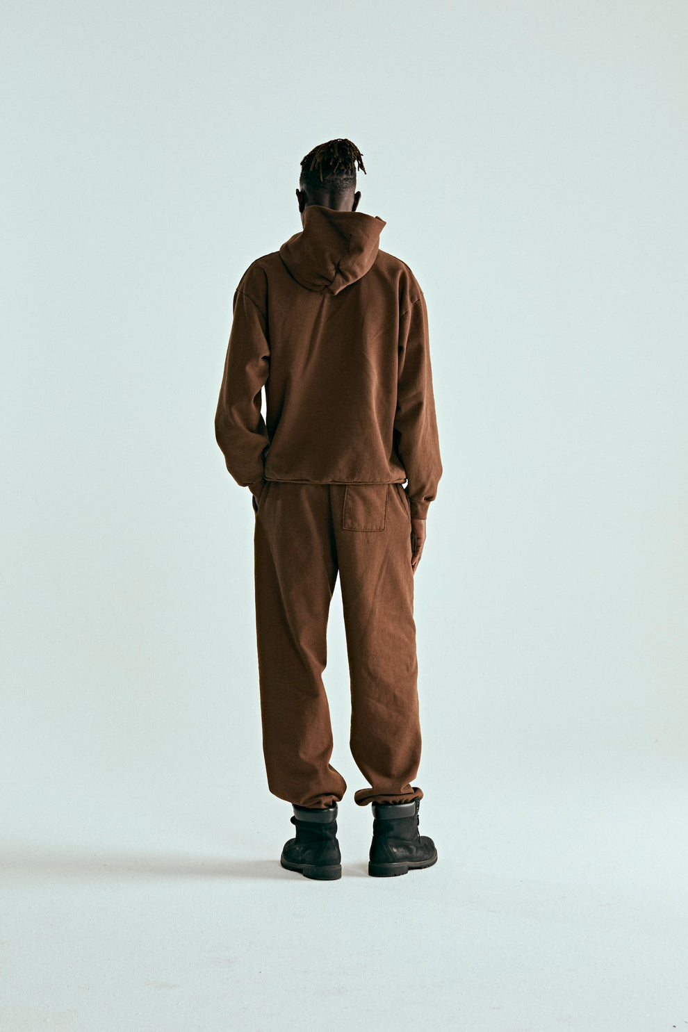 Back view of a person wearing a brown 13oz cotton fleece OG WEB HOODIE and matching sweatpants.