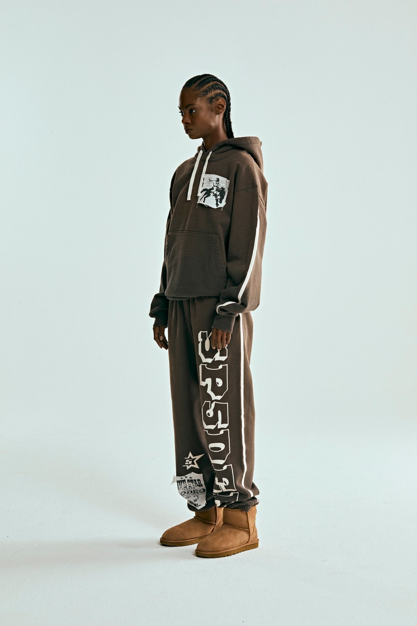Model in brown 5STAR Rodeo hoodie and sweatpants with white stripe details and distressed patches.