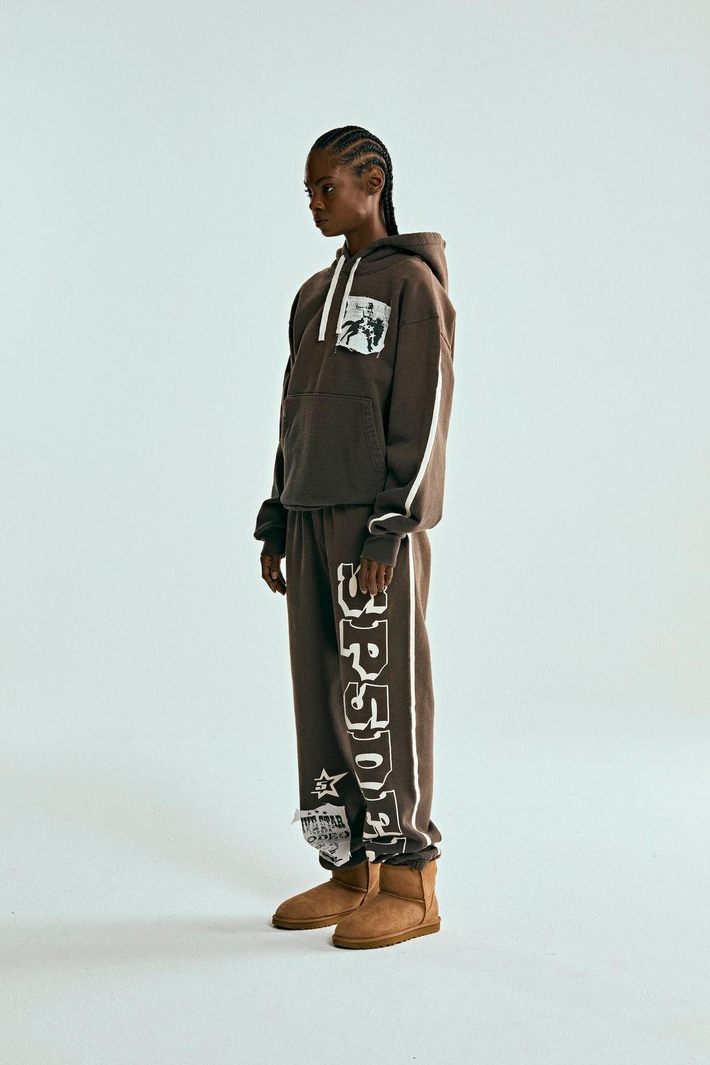Model in brown 5STAR Rodeo hoodie and sweatpants with white stripe details and distressed patches.