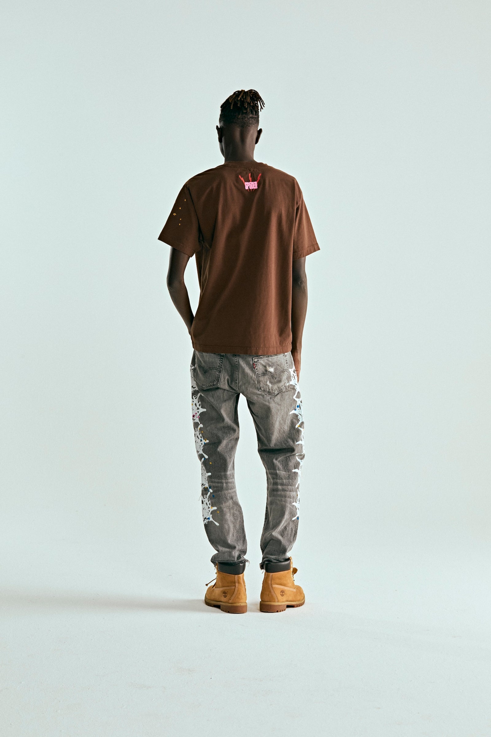 Brown cotton tee with puff print '555' angel numbers and OG web print on front, worn by a person facing away.