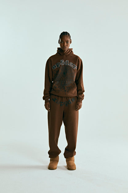 Brown cotton fleece hoodie with rhinestone "SP5DER" text and web print, paired with matching sweatpants.