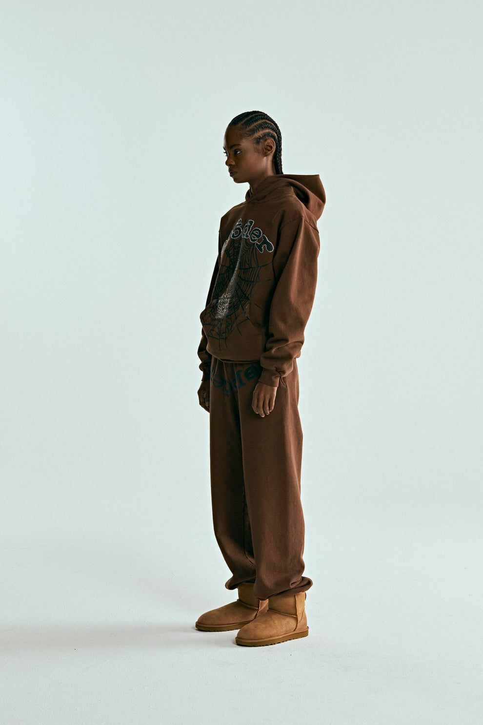 Brown OG WEB HOODIE and sweatpants set with rhinestone spider web print, worn by a person in profile.