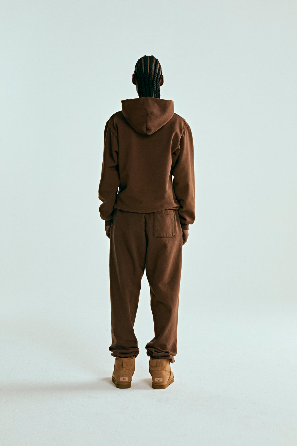 Person from behind wearing a brown OG WEB HOODIE and matching sweatpants, with UGG boots.