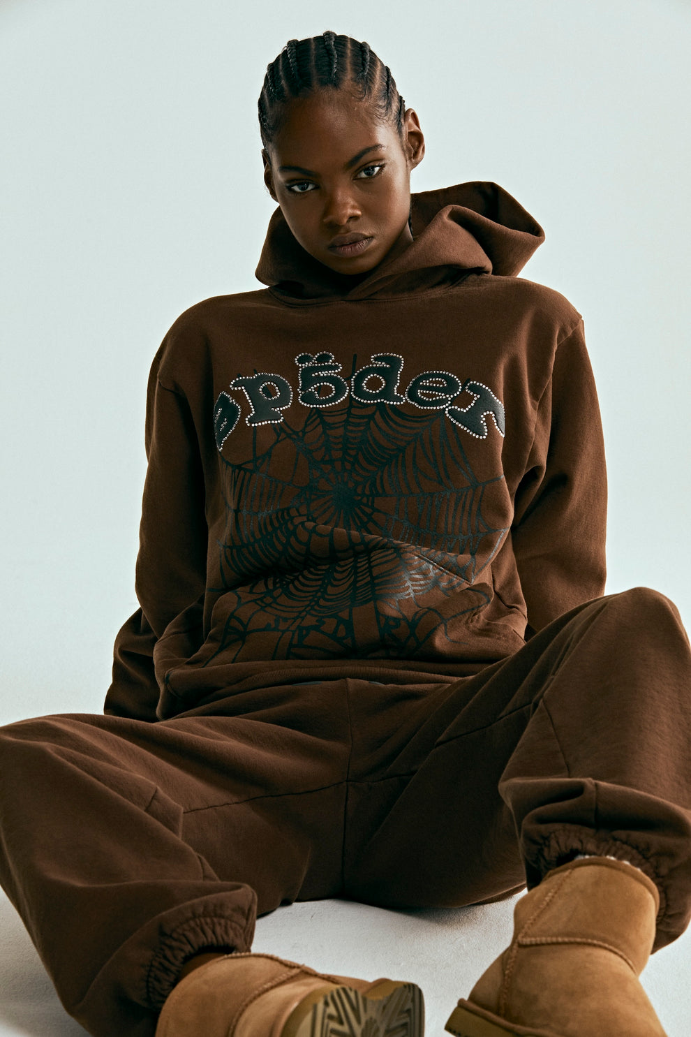 Brown 13oz cotton fleece OG WEB HOODIE with rhinestone "SP5DER" text and web print, worn by a model.