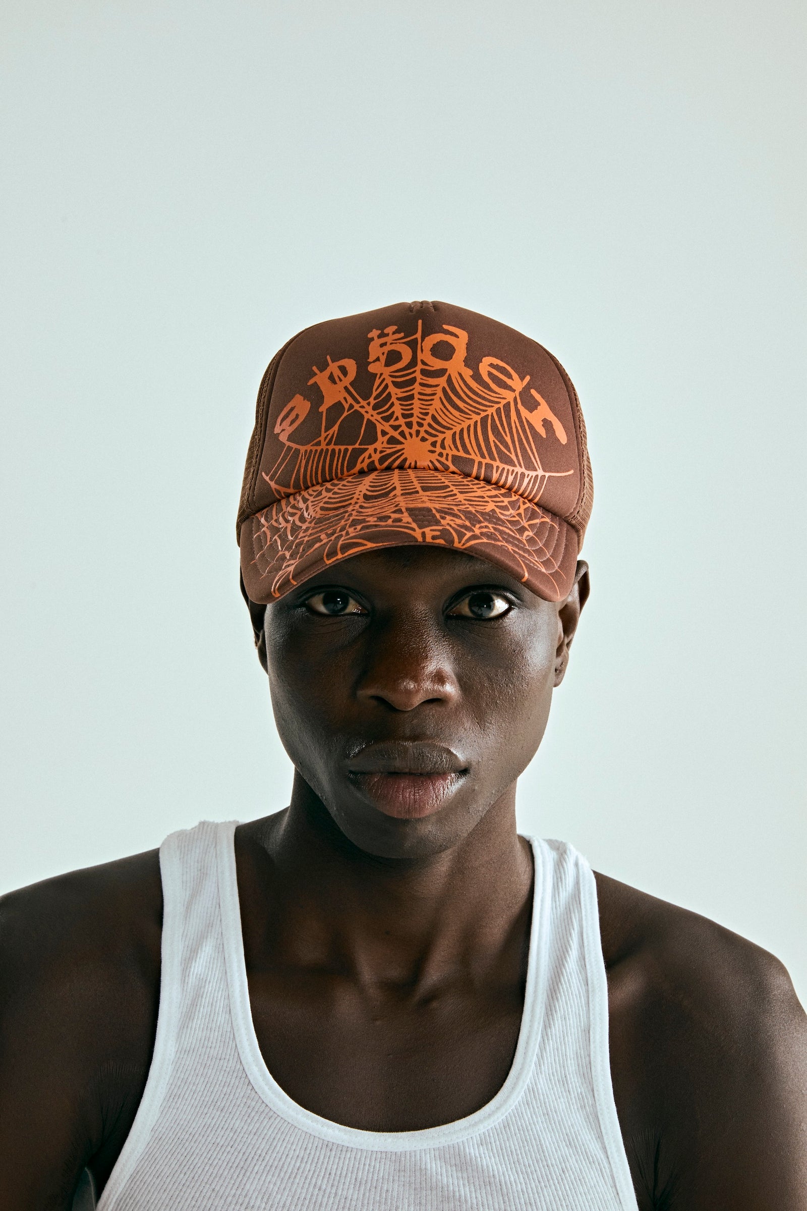 OG WEB V2 TRUCKER hat in brown with orange spider web print, curved brim, and adjustable snapback.