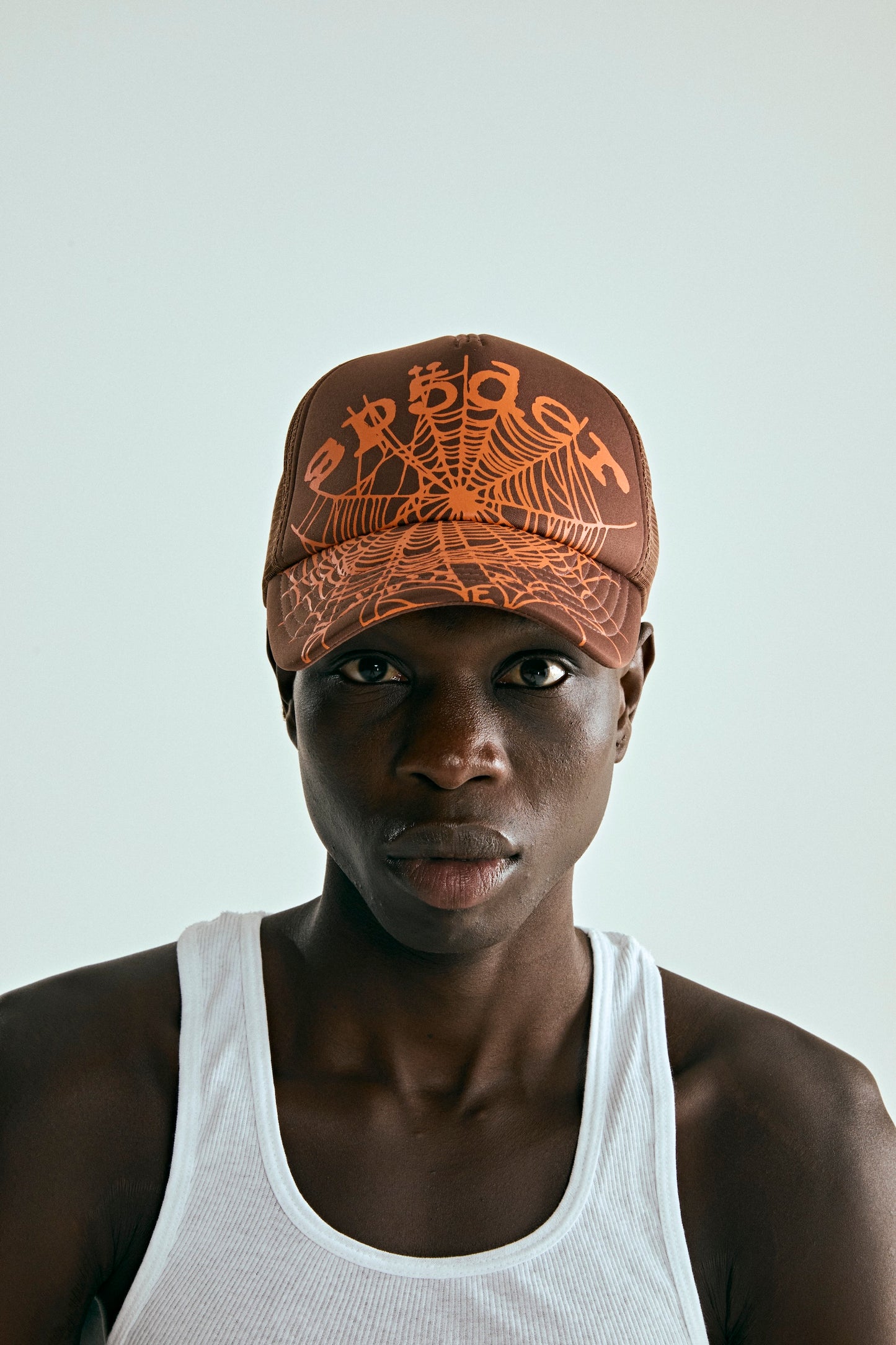 OG WEB V2 TRUCKER hat in brown with orange spider web print, curved brim, and adjustable snapback.