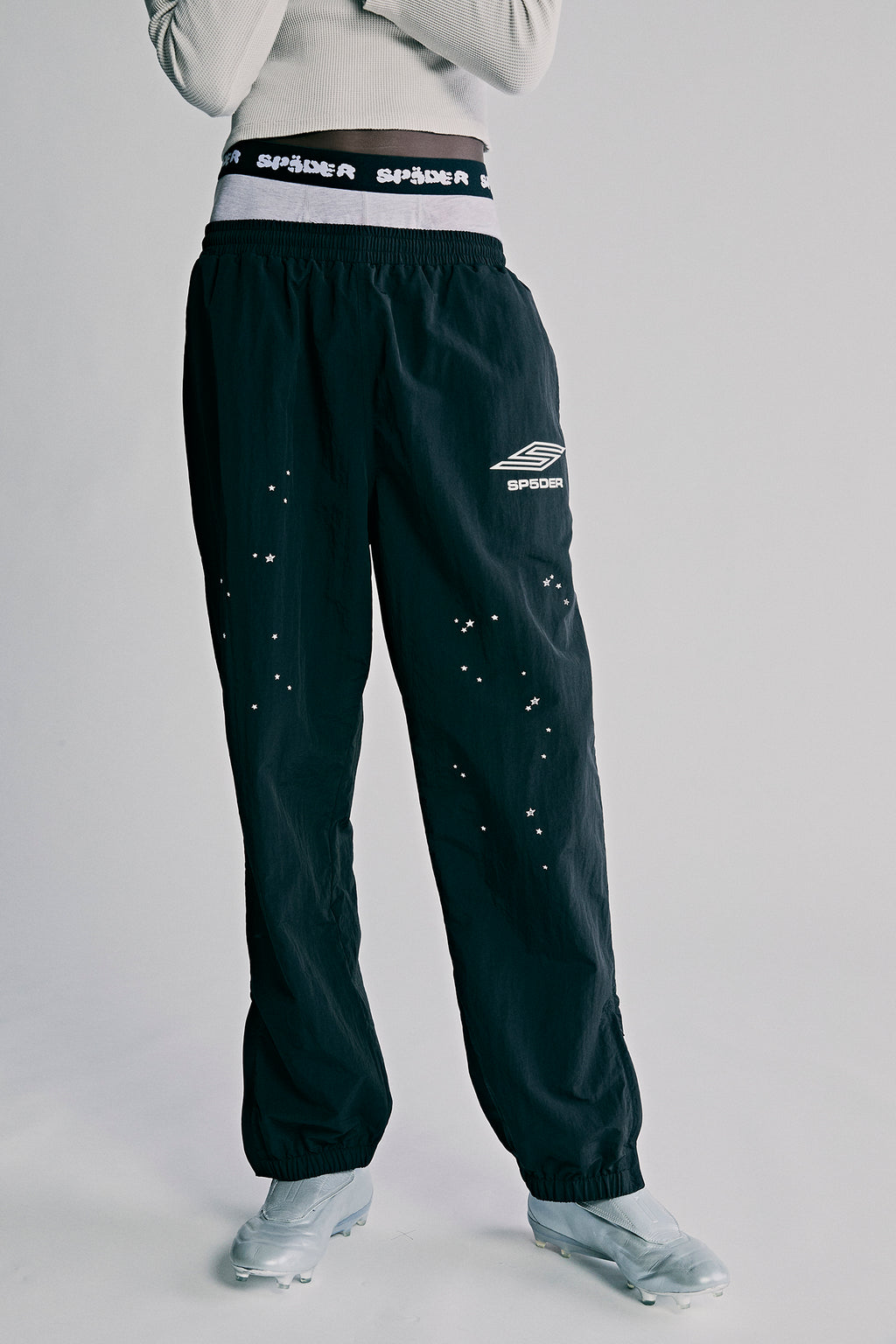 Black nylon ripstop SP5DER PRO WIND PANT with white logo, scattered star print, and zip cuffs.
