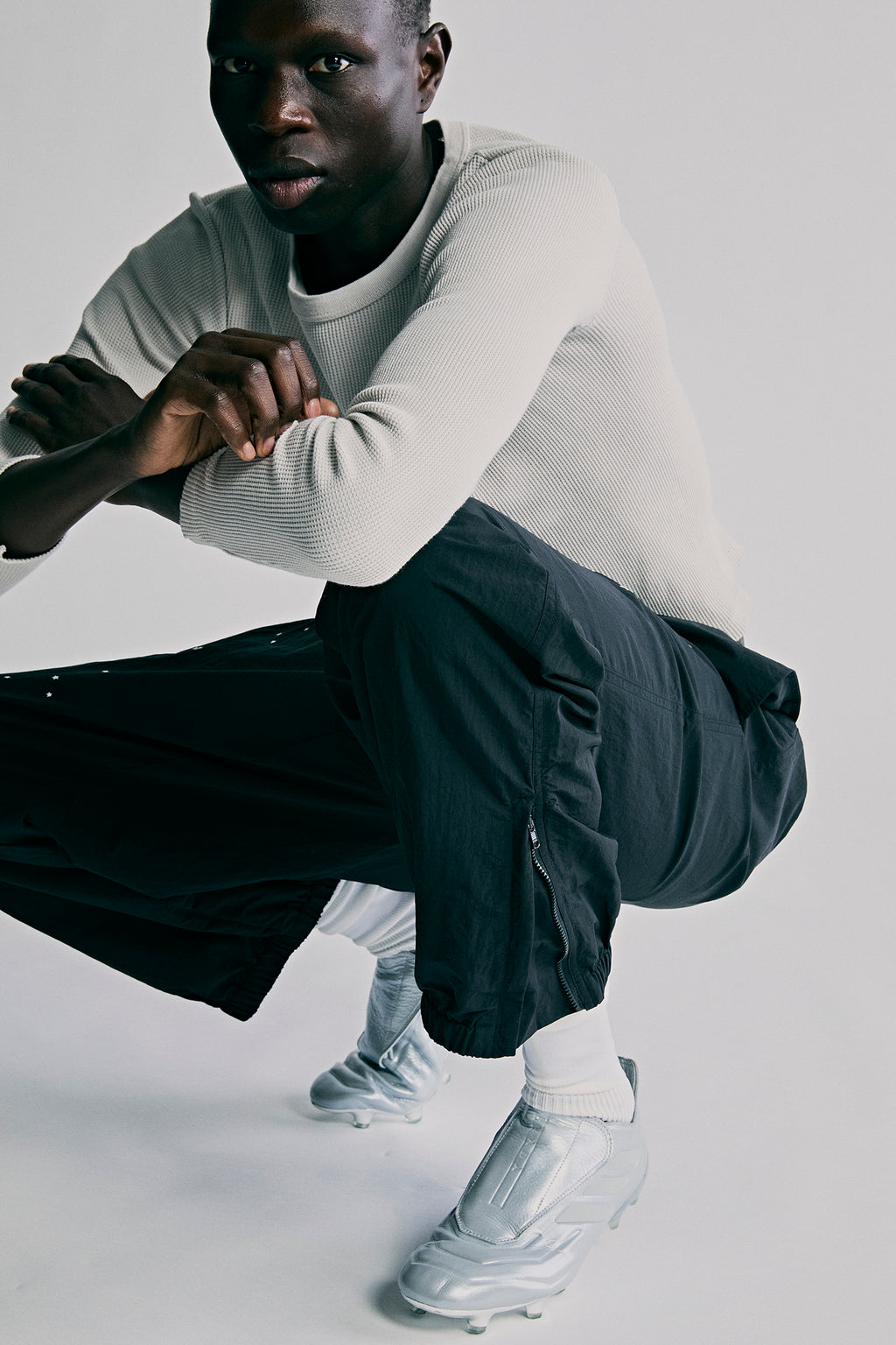 Black nylon ripstop SP5DER PRO WIND PANT with zip vents, worn by a man in a light sweater.