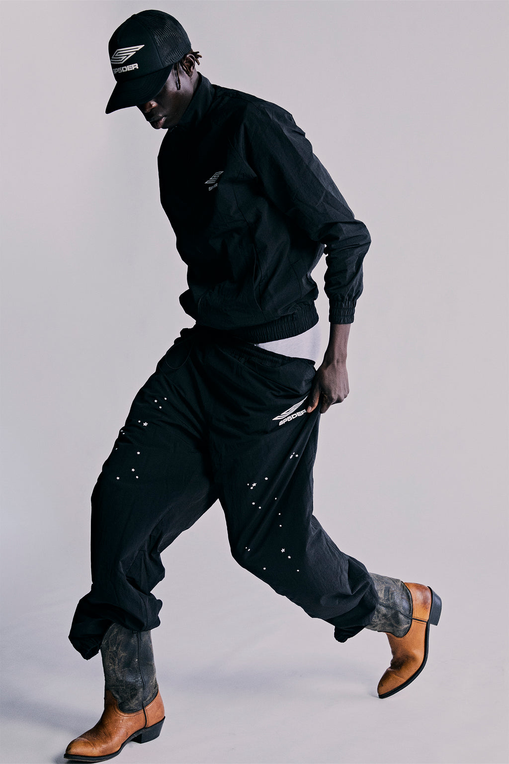 Black nylon ripstop SP5DER PRO WIND PANT with scattered star print, SP5 Pro logo, and zip cuffs.
