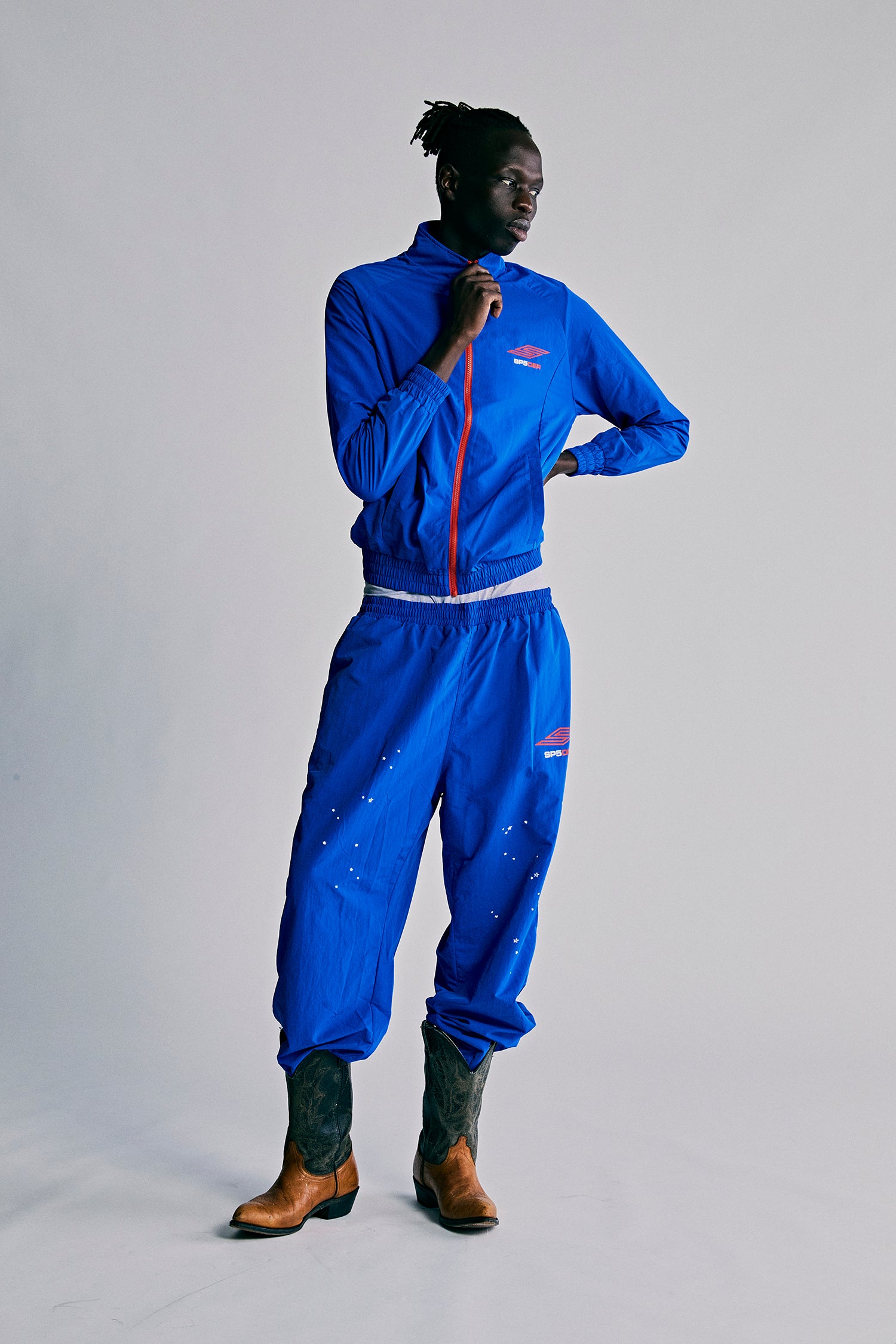 Blue nylon ripstop SP5DER PRO WIND PANT with scattered star print, bungee drawstring, and zip cuffs.
