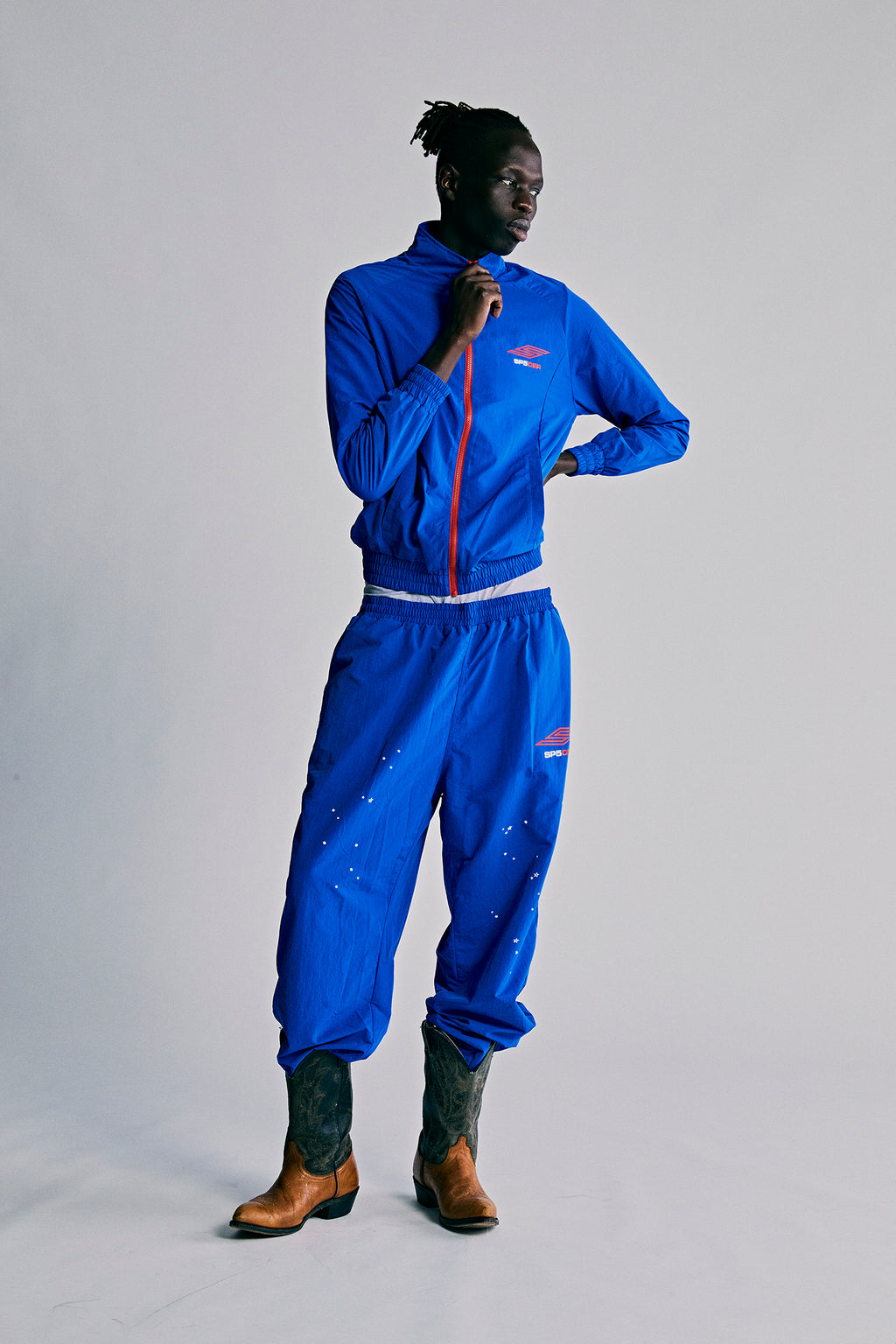 Blue nylon ripstop SP5DER PRO WIND PANT with scattered star print, bungee drawstring, and zip cuffs.