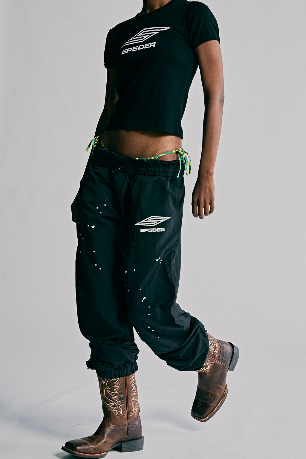 Black nylon ripstop SP5DER PRO WIND PANT with white logo, scattered stars, and zip cuffs.
