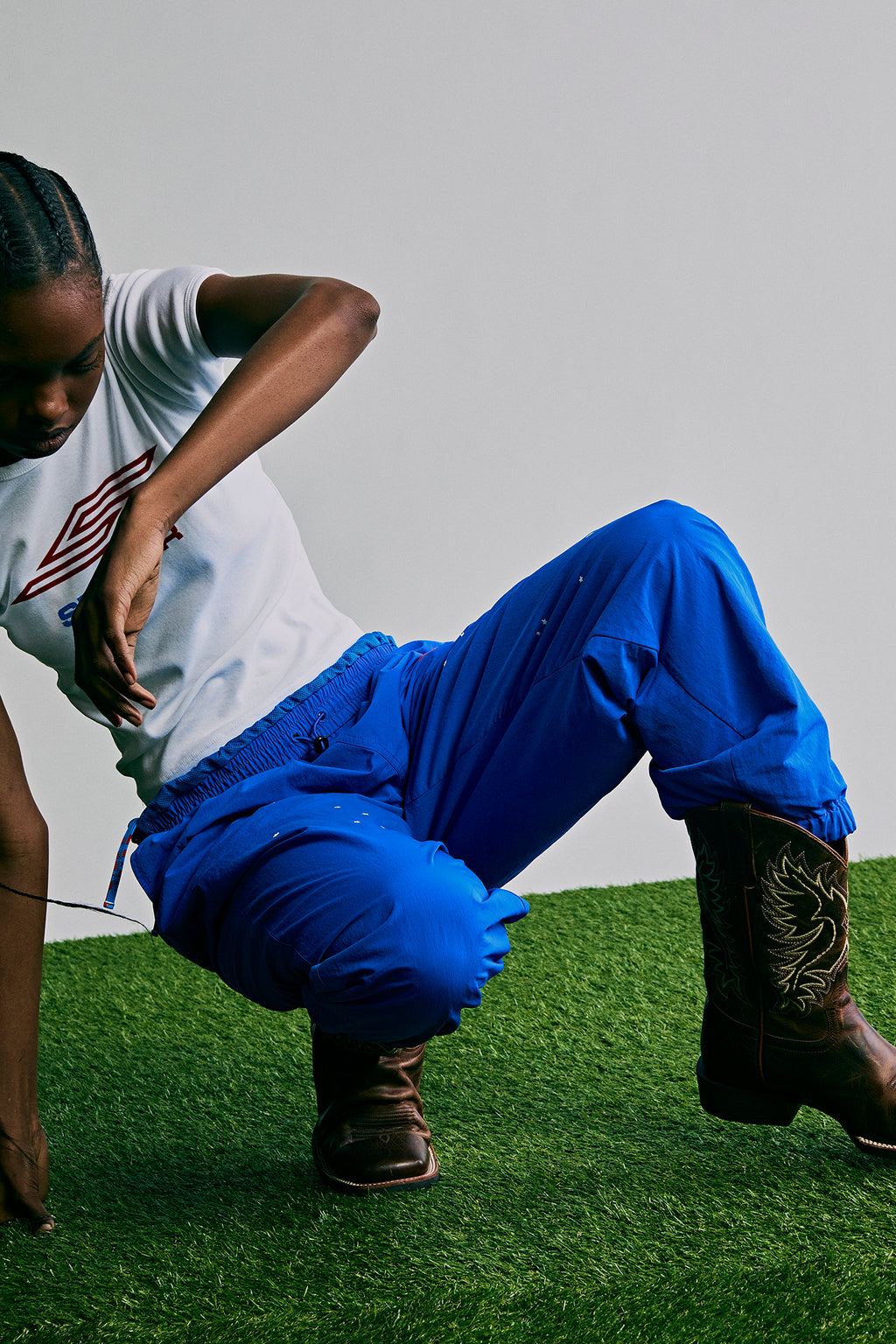 Person wearing royal blue SP5DER PRO nylon ripstop wind pants with elasticized cuffs and brown cowboy boots.