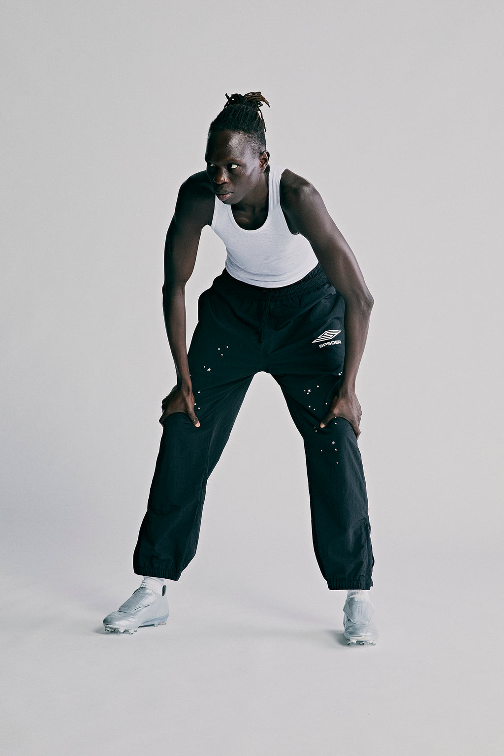 Black nylon ripstop SP5DER PRO WIND PANT with white logo, scattered star print, and zip cuffs.