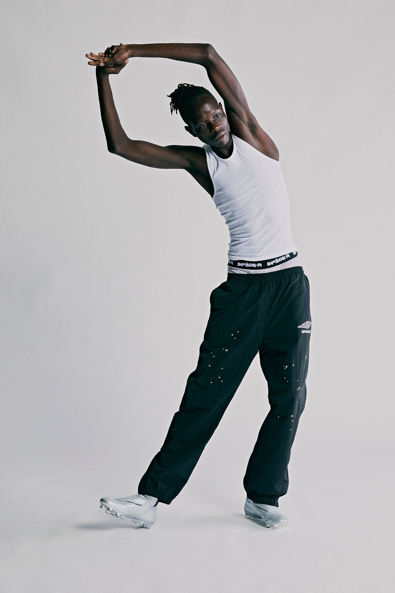 SP5DER PRO black nylon ripstop wind pants with white scattered star print, zip cuffs, and white logo.