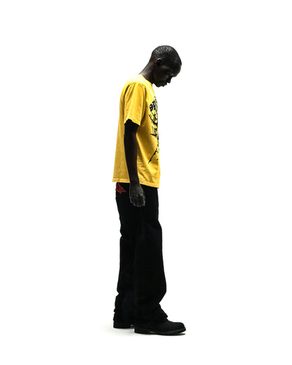 Man in yellow cotton tee with "SP5DER" text, rhinestones, and black pants.