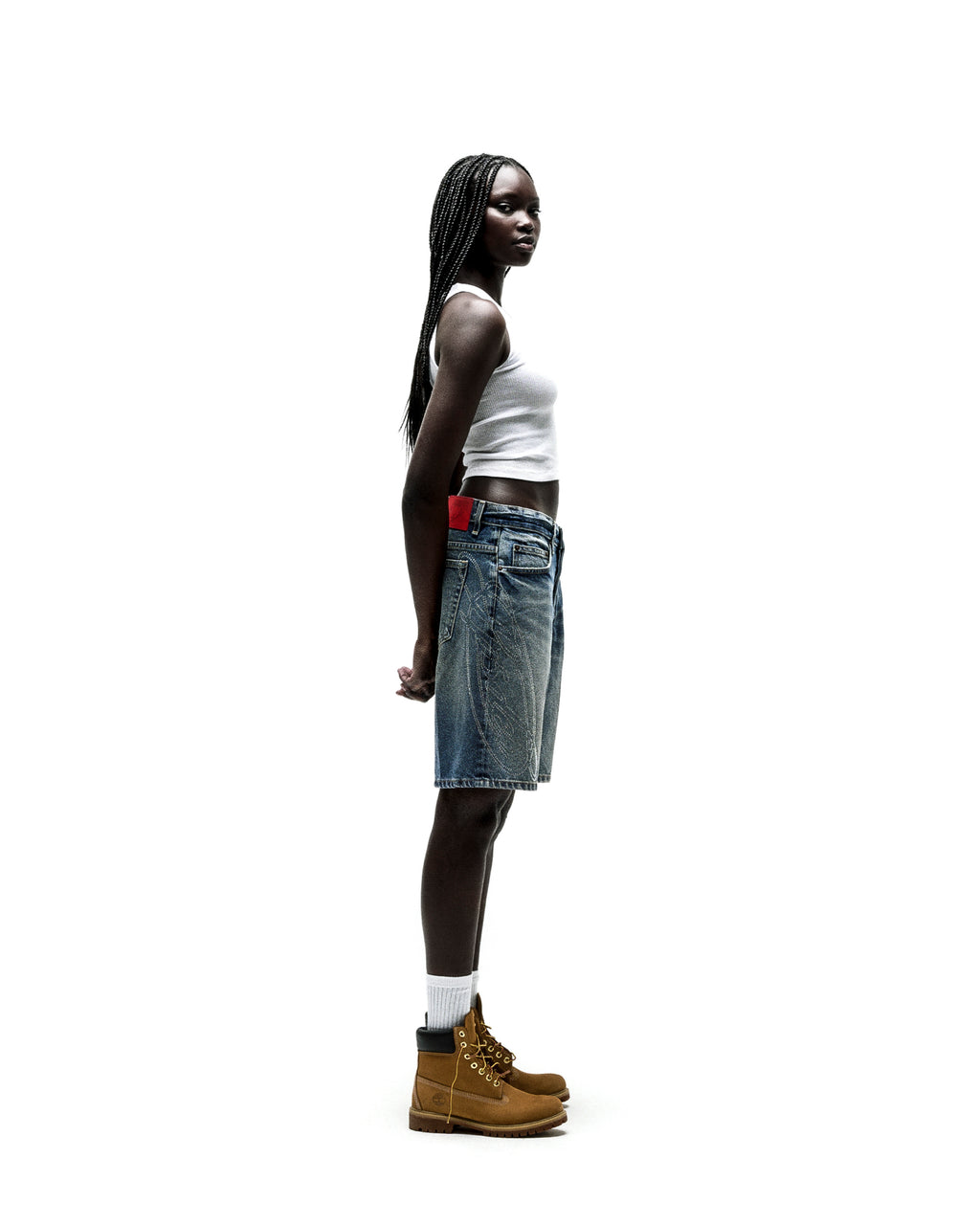 Model wearing vintage wash denim shorts with rhinestone web design and a red leather patch.